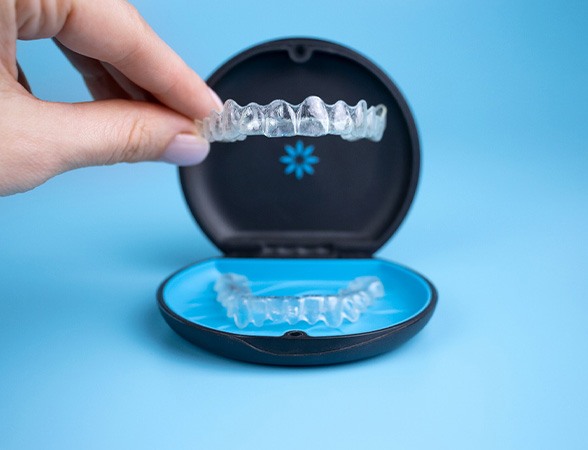 Fingers lifting Invisalign out of carrier case