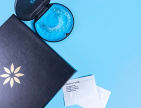 Bird’s eye view of Invisalign in case next to folder and packets of cleaning crystals