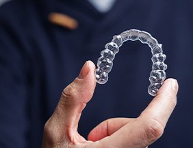 Dentist in navy scrubs holding Invisalign tray