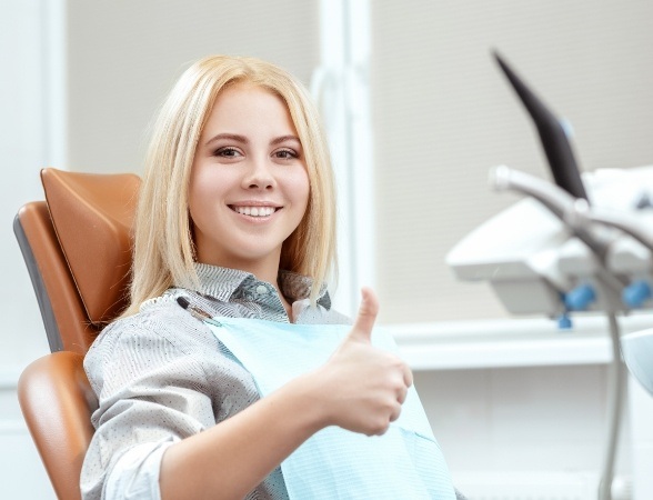 Young smiling woman giving thumbs up after wisdom tooth extraction