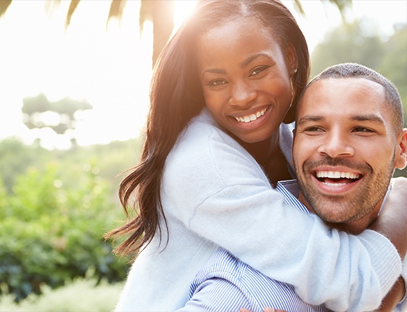 Man and woman smiling after tooth replacement with cosmetic dental implants