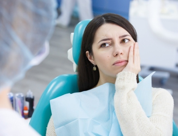 Woman in need of emergency dentistry holding cheek in pain