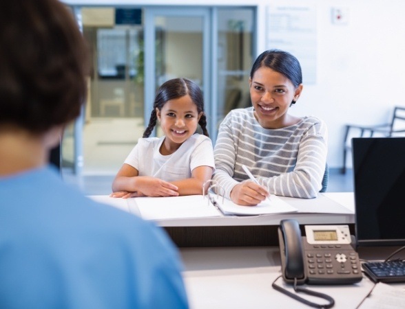 Mother and child discussing the cost of dental emergencies with dental team member