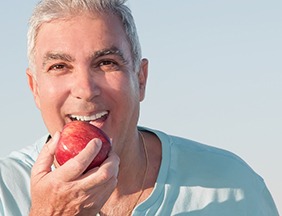 An older man eating an apple