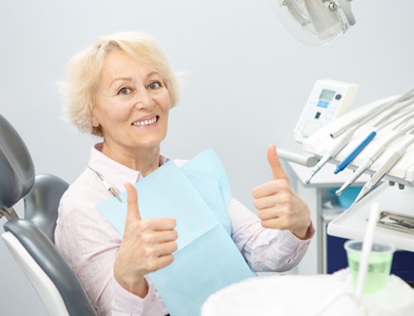 Senior woman giving two thumbs up at the dentist’s office