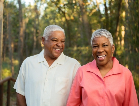 Man and woman smiling together enjoying the benefits of dental implants