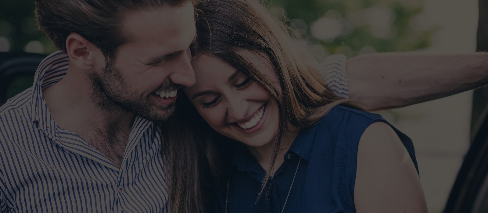 Man and woman smiling while looking down outdoors