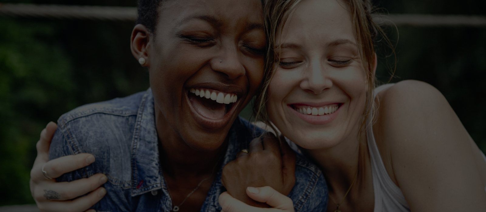 Two young women hugging and laughing outdoors