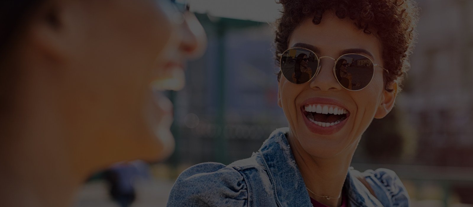 Two women with sunglasses laughing outdoors