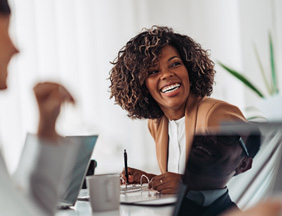 Woman smiling while taking notes during meeting