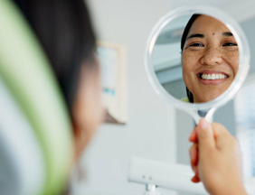 Woman smiling at reflection in dentist office
