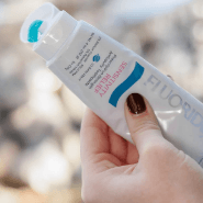 A person holds a tube of fluoride toothpaste in relation to Anthony Dillard, DDS Family & Cosmetic Dentistry.