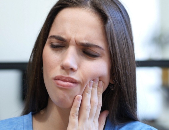 Woman in need of T M J therapy holding jaw in pain