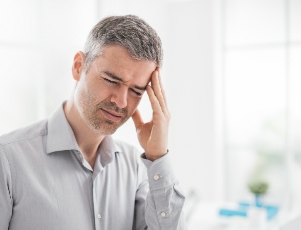 Man in need of T M J therapy holding head in pain