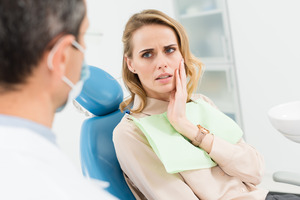 Concerned woman visiting her emergency dentist and touching jaw