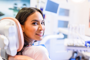 Female patient looking back and smiling while sitting in a dental chair