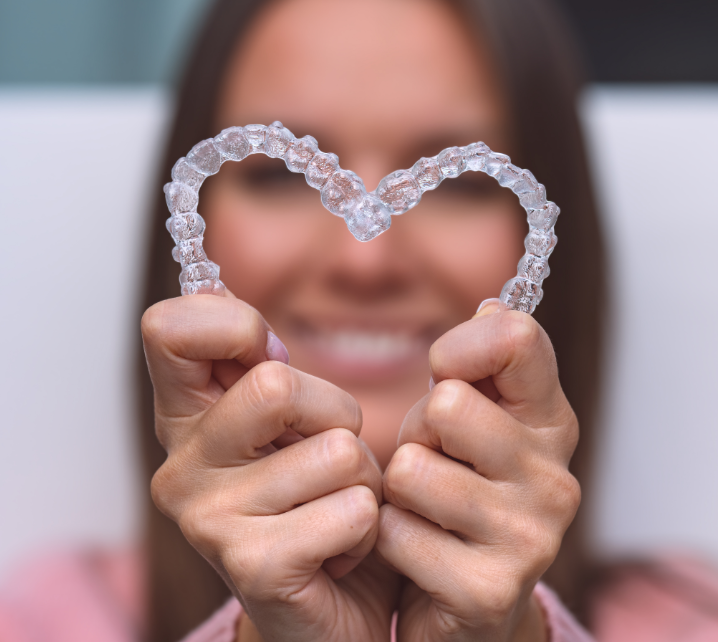 Woman holding clear aligners in heart shape